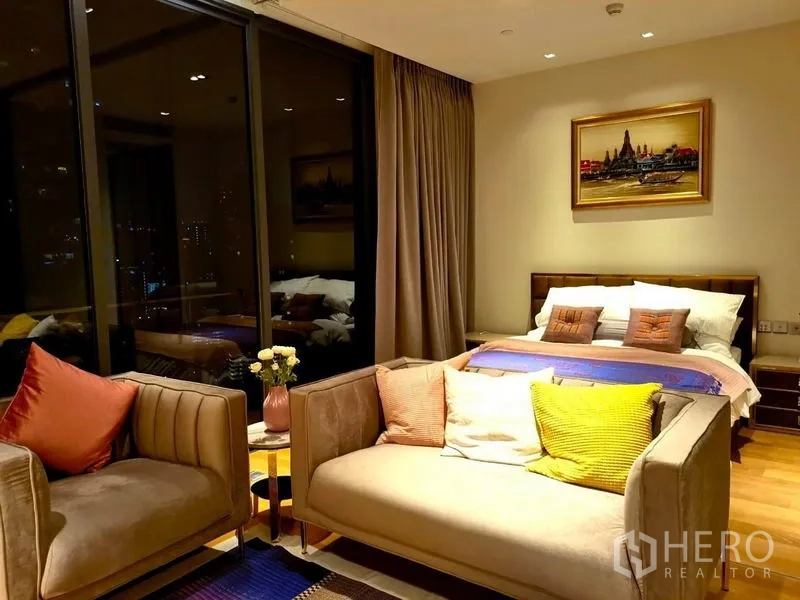 Condominium for rent in Khlong Toei, Bangkok - Night view of bedroom-living space with city lights outside large glass windows.