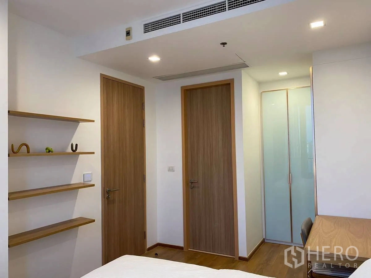 คอนโด for rent in Watthana, Bangkok - ห้องนอนมินิมอลพร้อมประตูไม้ ชั้นวาง โต๊ะทำงาน และตู้เสื้อผ้าบานฝ้า