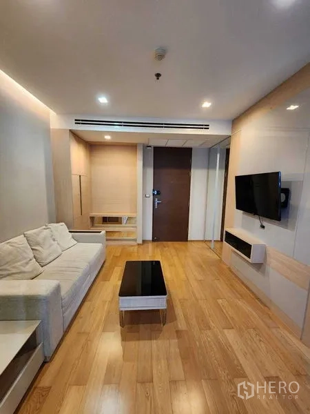 公寓 出售在Ratchathewi, Bangkok - 客厅另一角度，展示沙发、壁挂电视与极简收纳。