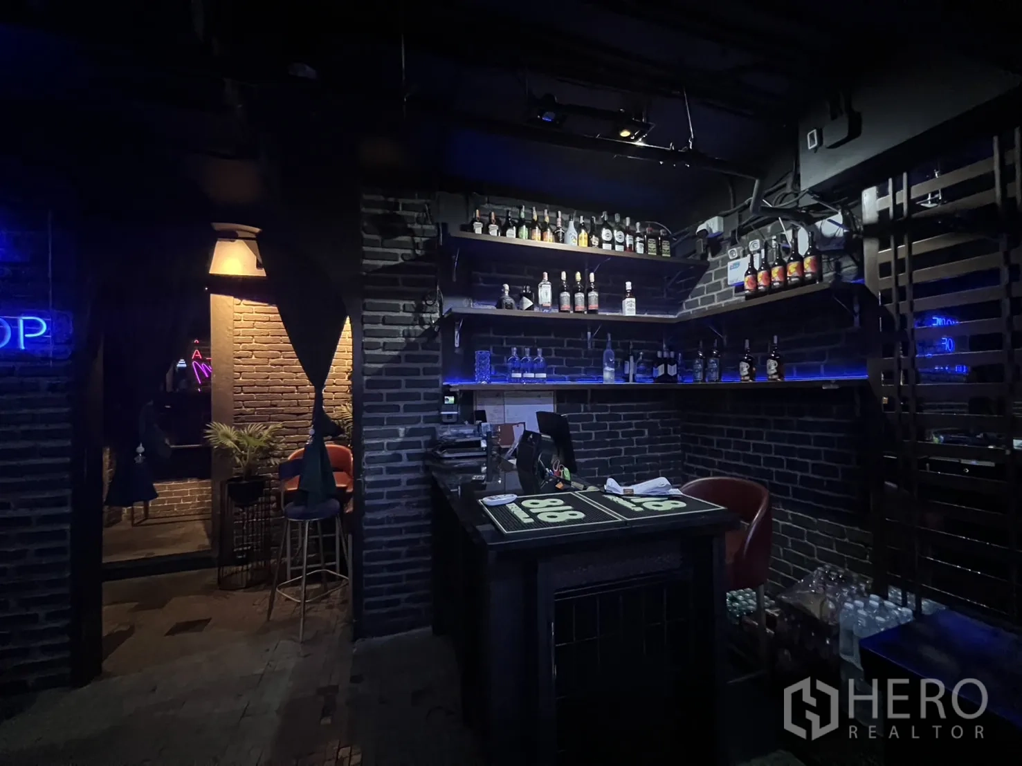 Retail Space for rent in Bangkok - Reception counter and bottle shelves in dimly lit brick interior.