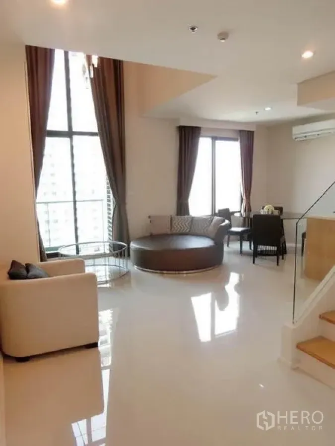 公寓 出租在Ratchathewi, Bangkok - 挑高客厅，落地窗、现代沙发与亮面地砖的复层公寓空间