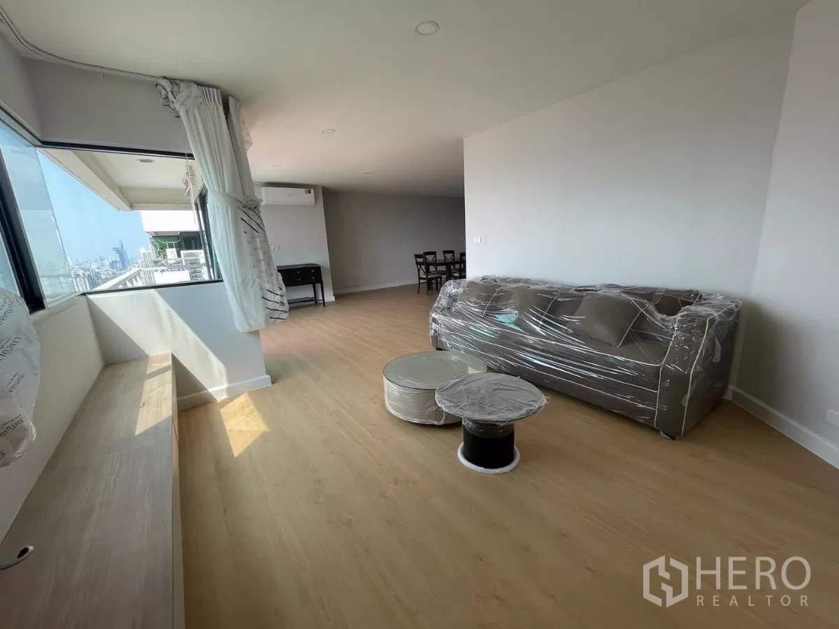 Condominium for rent in Sathon, Bangkok - Bright living room with corner windows, built-in bench, and wrapped sofa.