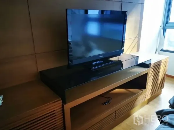 Condominium for sale in Khlong Toei, Bangkok - Flat-screen TV on built-in wooden media console beside a window.