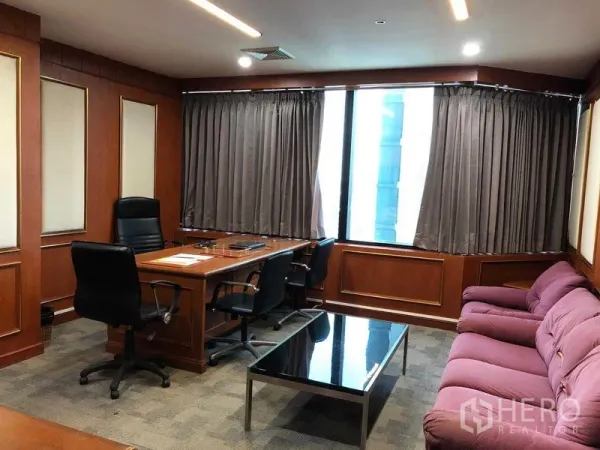 办公空间 出租在Ratchathewi, Bangkok - 会议室布局，配办公桌、沙发、带窗帘的大窗与木饰面墙。