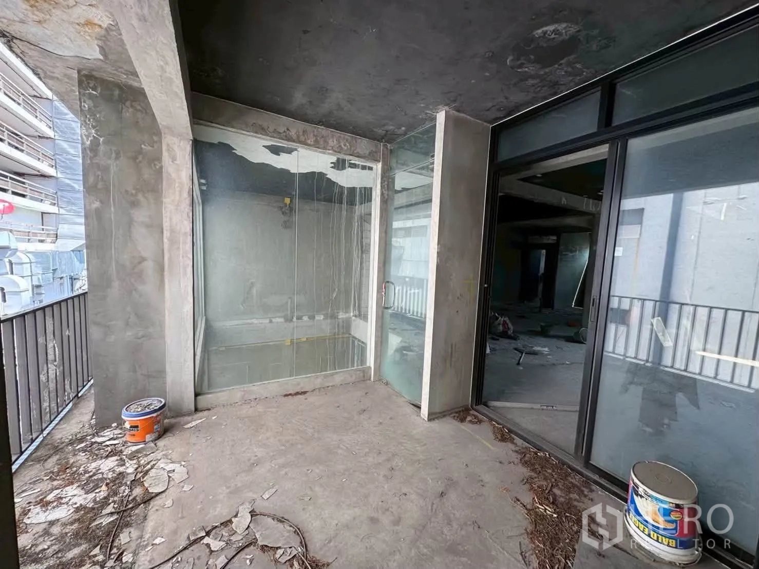 Shophouse for rent in Khlong Toei, Bangkok - Unfinished covered balcony with glass room, sliding doors, and metal railing.