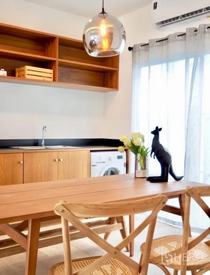 Townhouse for rent in Bang Phli, Samut Prakan - Kitchen-dining space featuring wooden cabinetry, sink, washer space and airy sheer curtains under a pendant light.