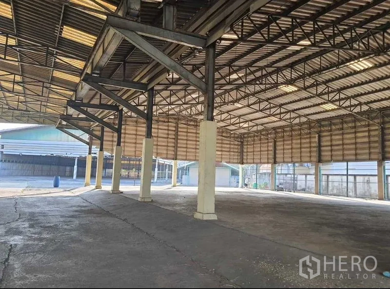 Warehouse for rent or sale in Mueang Pathum Thani, Pathum Thani - Open-span warehouse interior with high steel trusses, skylights and a durable concrete floor.