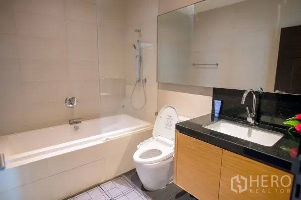 คอนโด ให้เช่าในWatthana, Bangkok - ห้องน้ำสมัยใหม่พร้อมอ่างอาบน้ำและฝักบัว กั้นกระจก กระจกบานใหญ่ และเคาน์เตอร์ท็อปหินสีดำ