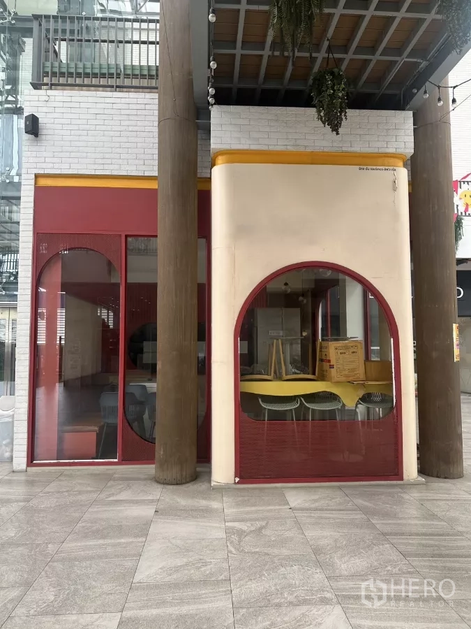 零售空间 出租在Khlong Toei, Bangkok - 底层店面，红色拱形玻璃立面与木柱，位于有顶中庭。
