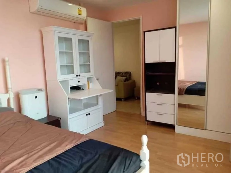 Condominium for rent in Khlong Luang, Pathum Thani - Bright bedroom with white desk, mirrored wardrobe and wood flooring at Nusasiri Grand Condo.