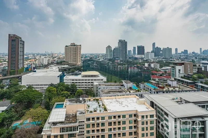 Condominium for sale in Khlong Toei, Bangkok - High-floor city skyline view over Sukhumvit and Ekkamai with towers, greenery and a golf driving range under a cloudy sky.