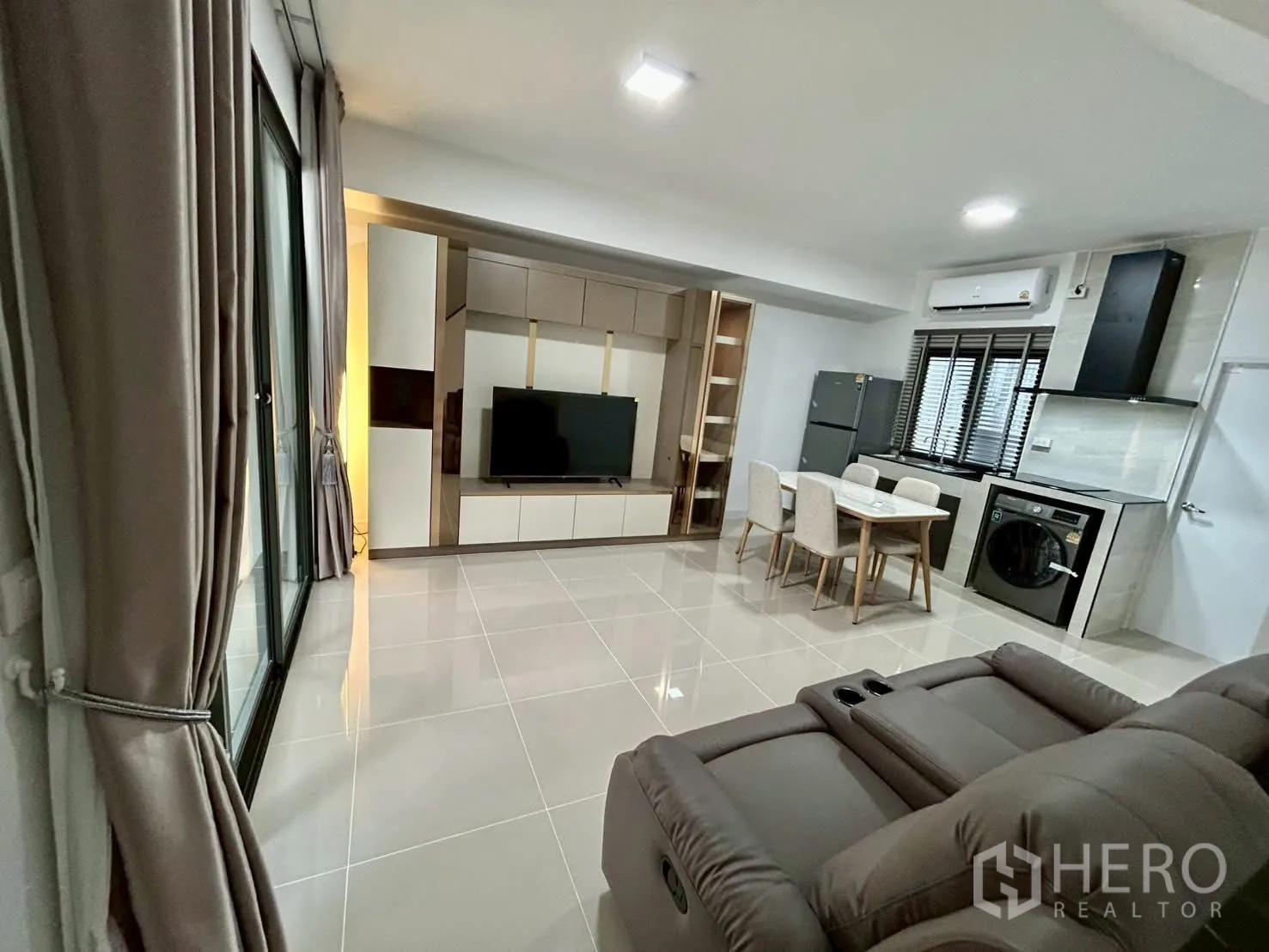 Townhouse for rent in Bang Phli, Samut Prakan - Spacious living-dining room with TV wall, dining set and kitchen.