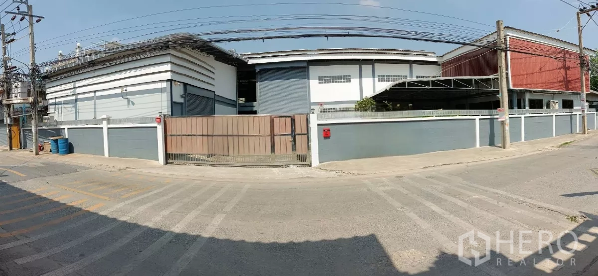 工厂 出租或出售在Bang Khun Thian, Bangkok - 曼谷邦坤天区独栋工厂外观，带大门与围墙，卷门与架空电线的街景。