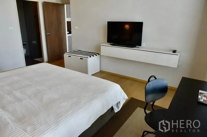 Condominium for rent in Phaya Thai, Bangkok - Bedroom view toward wall-mounted TV shelf and doorway to bathroom in a modern condo.