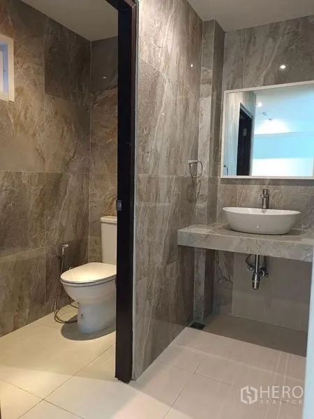 Retail Space for rent - Modern bathroom with vanity and adjacent toilet finished in stone-look tiles.