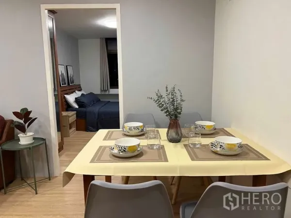 公寓 出租在Ratchathewi, Bangkok - 餐桌摆放四人餐具，木地板，门内可见卧室与窗户。