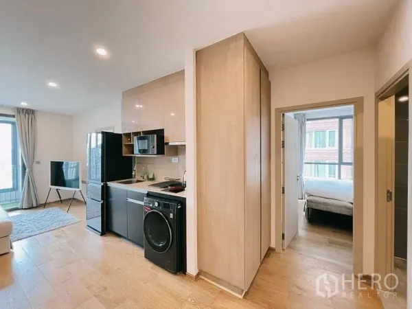 Condominium for rent in Ratchathewi, Bangkok - Compact kitchen with built‑in cabinets and corridor leading to a bedroom.