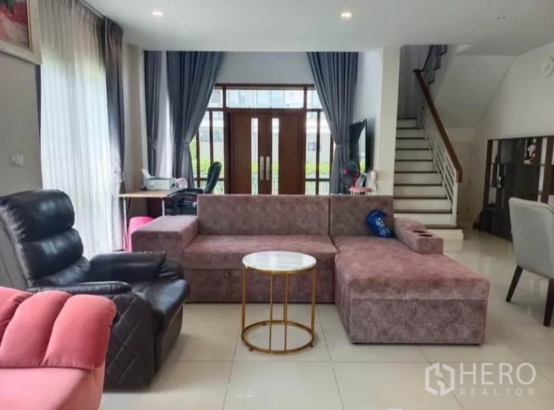 Detached House for rent - Spacious living room with L‑shaped sofa, recliner and staircase leading to the upper floor.