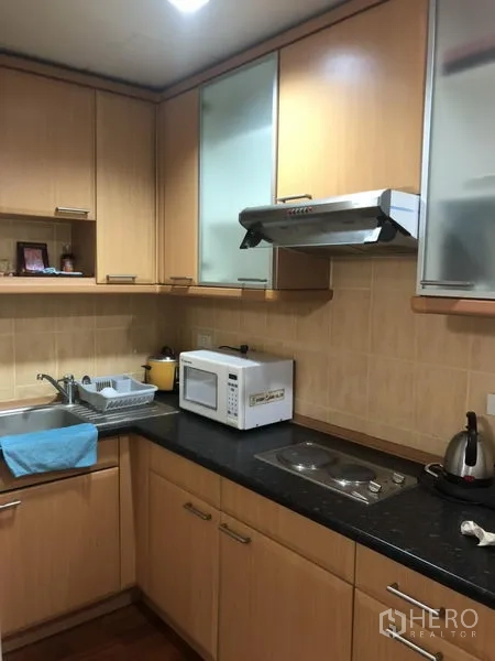 公寓 出租在Bang Rak, Bangkok - 转角厨房，木质橱柜、石质台面、水槽、炉灶、抽油烟机与微波炉
