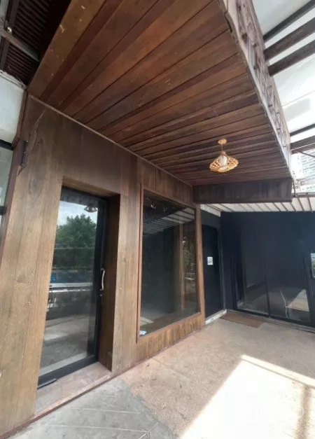 零售空间 出租 - 木饰店面转角，遮雨棚下带吊灯的入口。