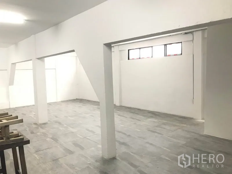 办公空间 出租在Watthana, Bangkok - 开放式办公室内景：白色墙面、灰色地砖、承重立柱与高位窗。