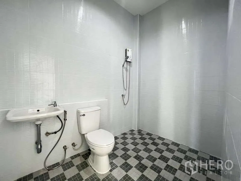 Warehouse for rent or sale - Clean restroom with toilet, sink and wall‑mounted shower heater.