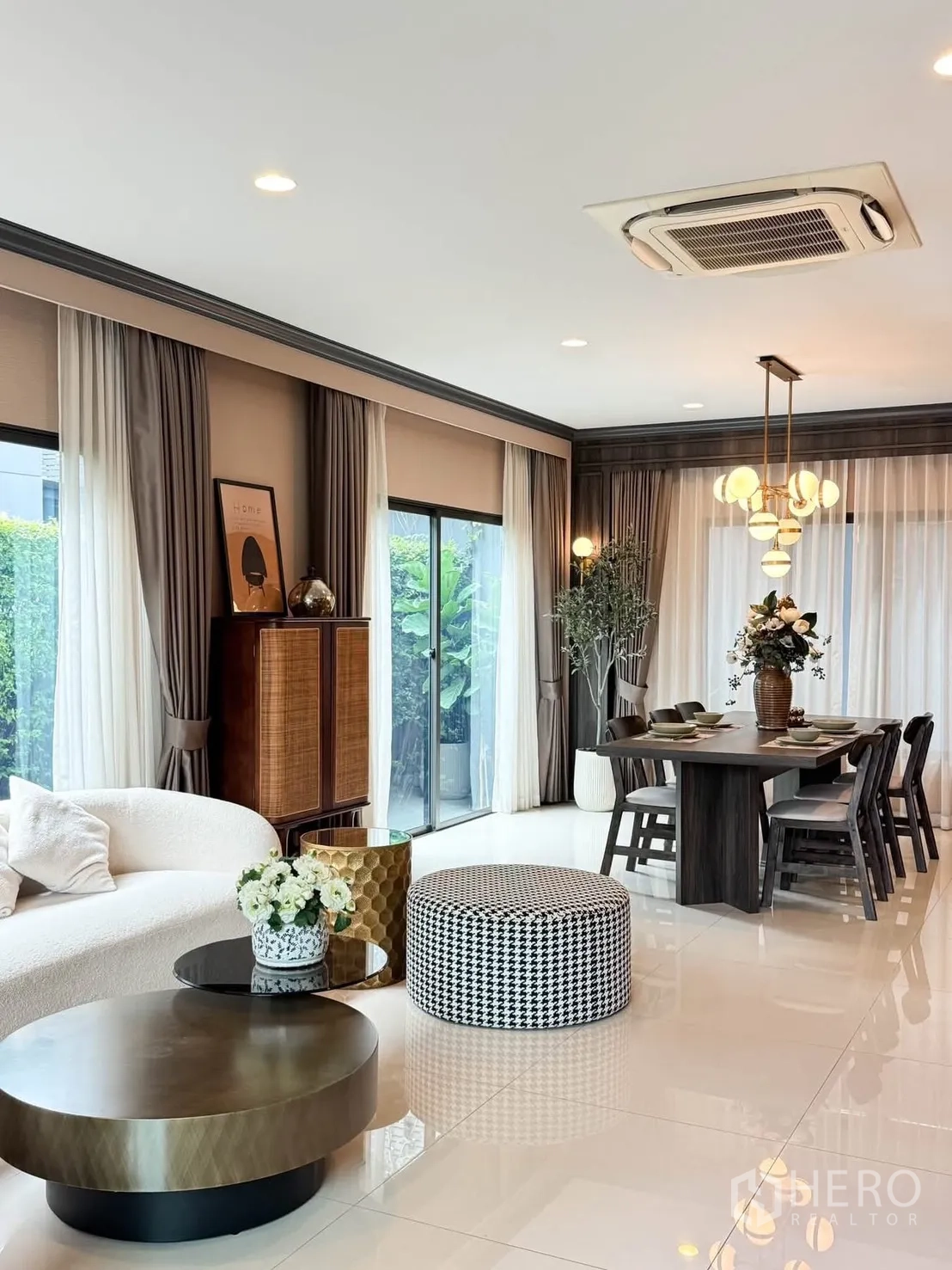 Detached House for rent in Bang Kapi, Bangkok - Open-plan living and dining area with sofa, round coffee tables, sliding glass doors, and pendant lighting.