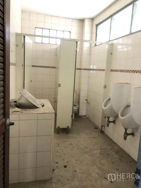 Factory for rent in Prawet, Bangkok - Factory restroom with tiled stalls and urinals.