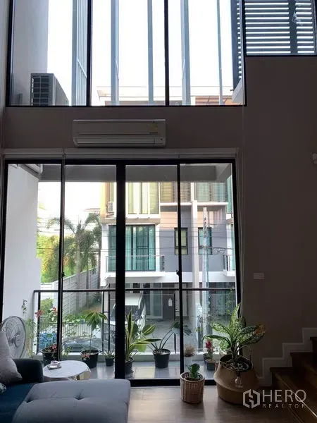 联排别墅 出租在Khlong Toei, Bangkok - 挑高客厅，落地窗与阳台景观。