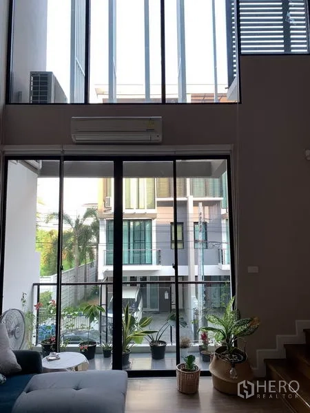 联排别墅 出租在Khlong Toei, Bangkok - 挑高客厅，落地窗与阳台景观。
