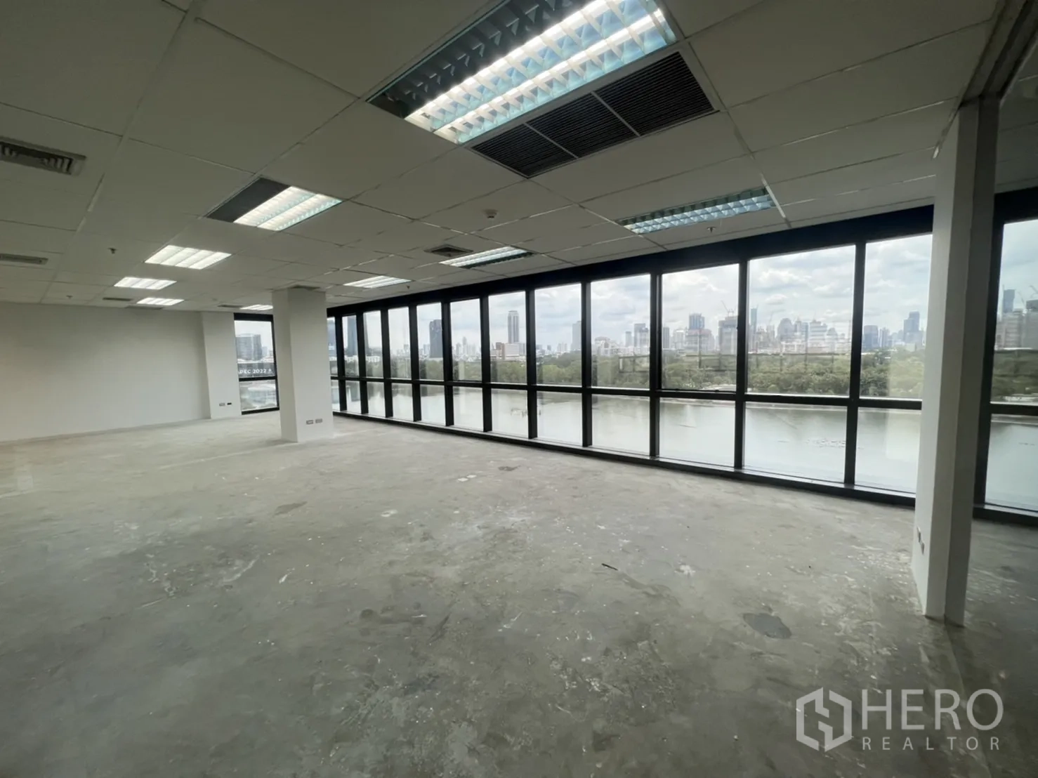 Office Space for rent in Watthana, Bangkok - Bright corner office area with panoramic windows overlooking a park lake and skyline.