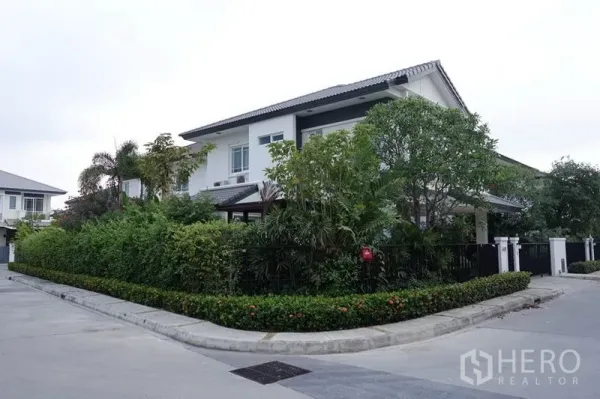 独立式住宅 出售在Bang Kapi, Bangkok - 角落位置的两层白色独栋别墅，黑色围栏与茂密绿篱，环境安静。