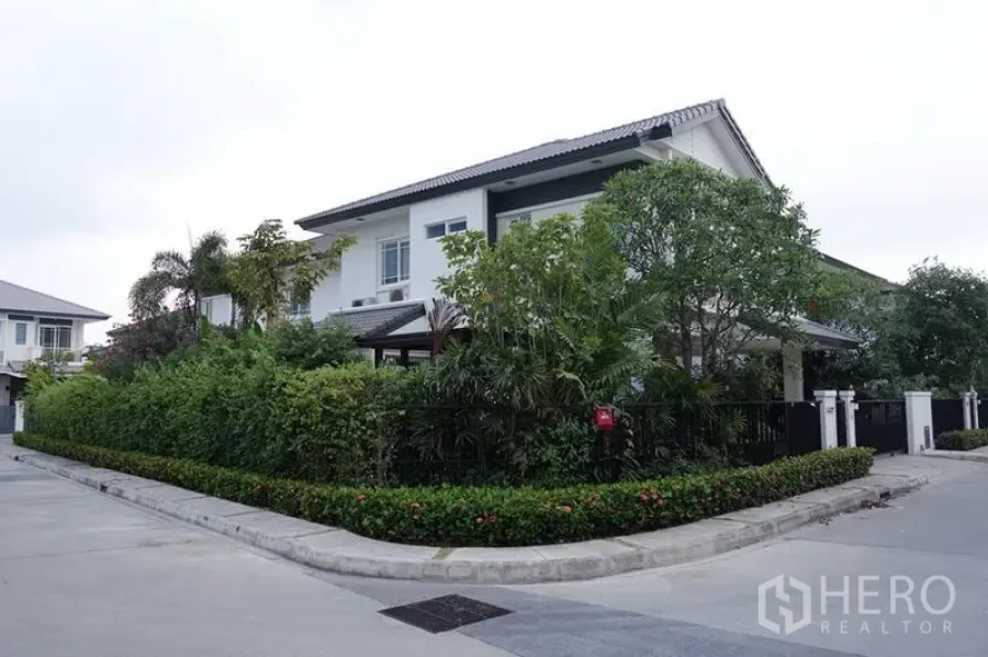 Detached House for sale in Bang Kapi, Bangkok - Corner two-storey detached house with white facade, black fence and lush hedges in a quiet Bang Kapi estate.