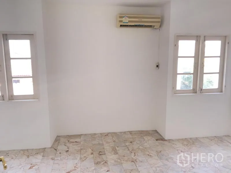 Townhouse for rent in Chatuchak, Bangkok - Second bedroom with marble-look floors, white walls, corner windows and air conditioning.
