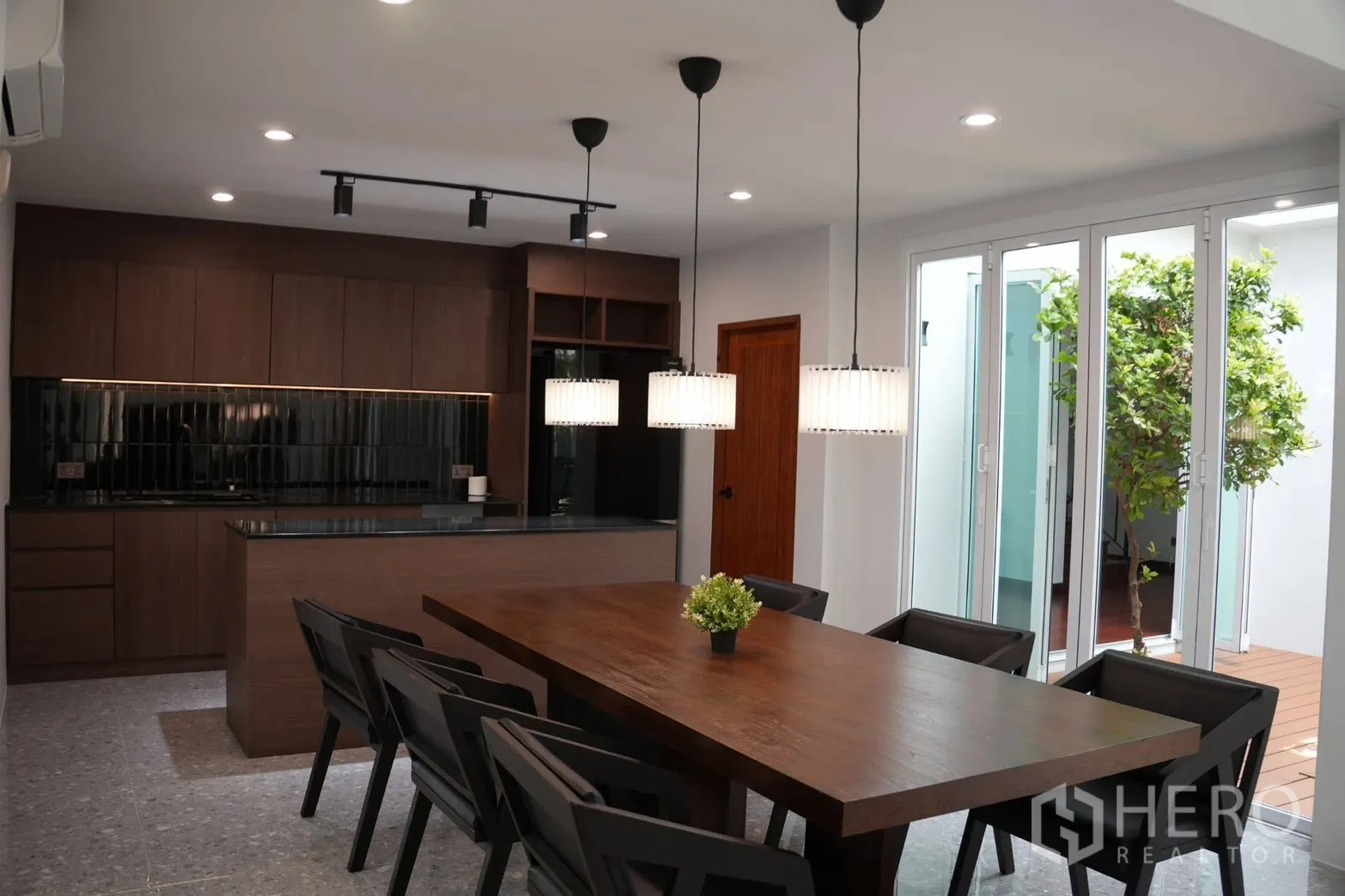 บ้านเดี่ยว for rent in Suan Luang, Bangkok - พื้นที่ทานอาหารพร้อมโคมไฟแขวนติดกับประตูบานเลื่อนเปิดสู่คอร์ทยาร์ด