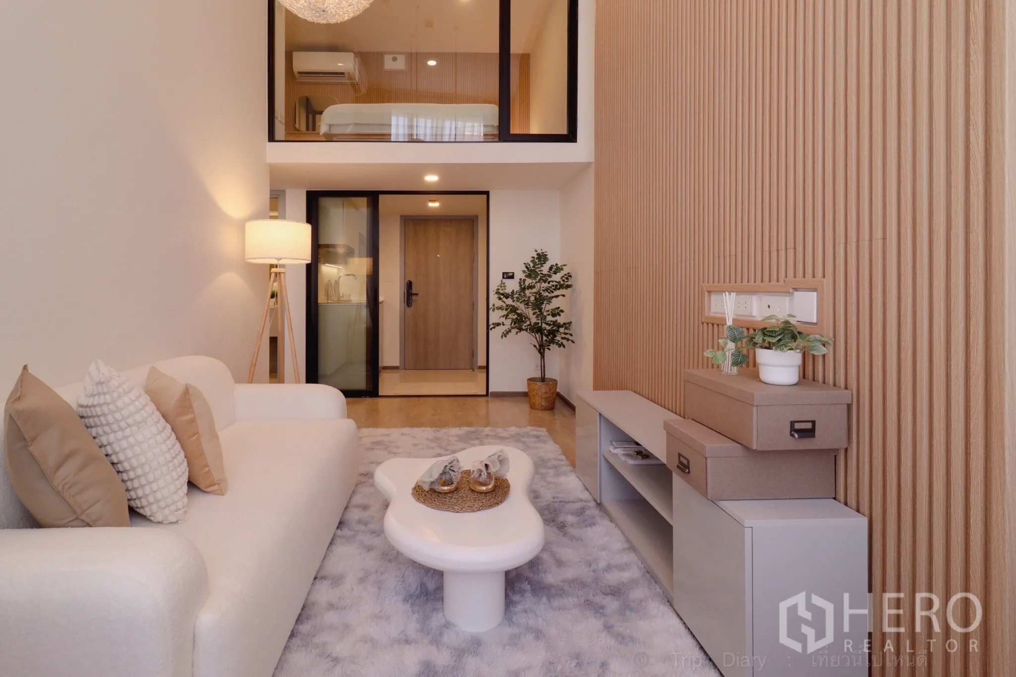 คอนโด for rent in Huai Khwang, Bangkok - ห้องนั่งเล่นสไตล์มูจิแบบดูเพล็กซ์ เพดานสูง 4 ม. โซฟาสีขาว โต๊ะกลางดีไซน์ ผนังลายไม้ ห้องนอนชั้นลอย และครัวกั้นกระจก