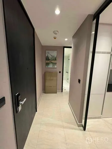 Condominium for rent in Bang Rak, Bangkok - Entry hallway with dark door, tiled floors and a view into a modern bathroom