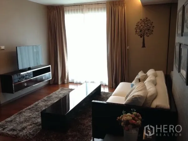 公寓 出租在Watthana, Bangkok - 客厅配长形茶几、电视柜、大窗帘与长绒地毯，氛围舒适。