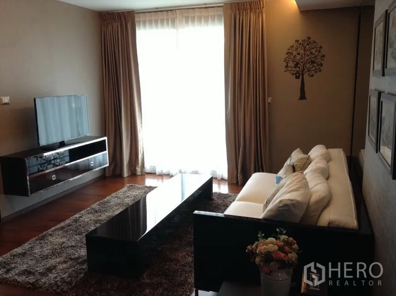 公寓 出租在Watthana, Bangkok - 客厅配长形茶几、电视柜、大窗帘与长绒地毯，氛围舒适。