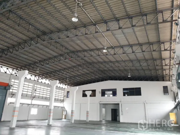 工厂 出租在Bang Pakong, Chachoengsao - 仓库内部空间开阔，钢结构屋架挑高，吊灯与白色支柱清晰可见。