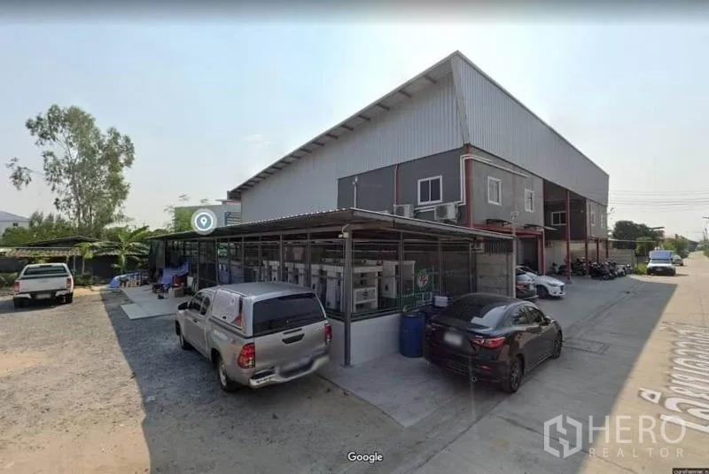 Warehouse for rent in Lam Luk Ka, Pathum Thani - Side view of the warehouse with a covered utility area and multiple parking spaces.