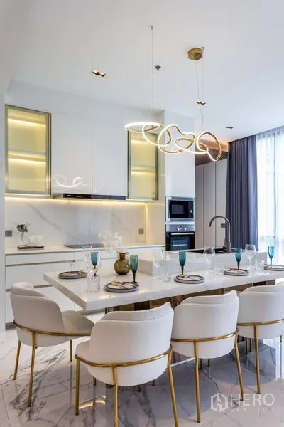 Condominium for rent in Khlong Toei, Bangkok - Contemporary kitchen and dining area with marble surfaces and sculptural lighting.