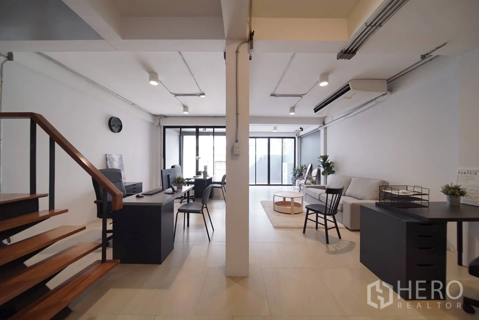 Townhouse for rent in Watthana, Bangkok - Ground floor view toward the glass-front entry showing desks and lounge seating.