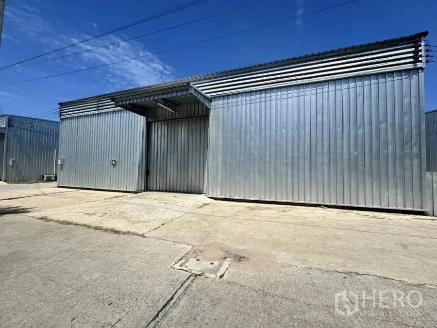 货栈 出租在Bang Lamung, Chon Buri - 邦拉蒙金属板仓库外观，超大推拉门与宽阔混凝土场地。