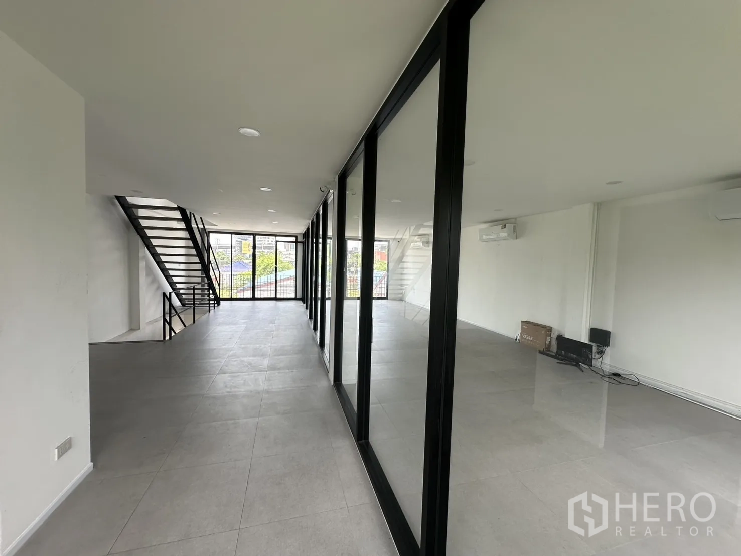 Home Office for rent or sale in Bang Na, Bangkok - Long corridor with floor-to-ceiling glass partitions and city view ahead.