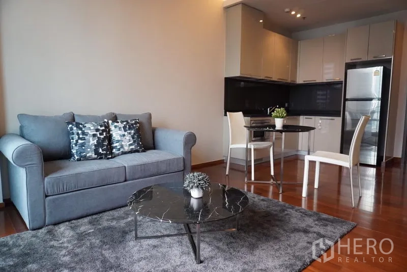 Condominium for rent in Watthana, Bangkok - Open-plan living area with sofa, dining table and fitted kitchen.