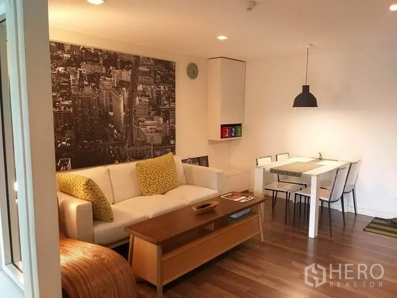 公寓 出租在Watthana, Bangkok - 明亮的客餐厅，白色沙发、城市壁画与温暖木地板。