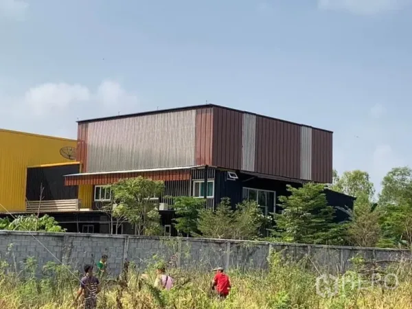 工厂 出售在Thanyaburi, Pathum Thani - 主厂房旁的两层金属覆面办公楼，周围绿化与围墙。