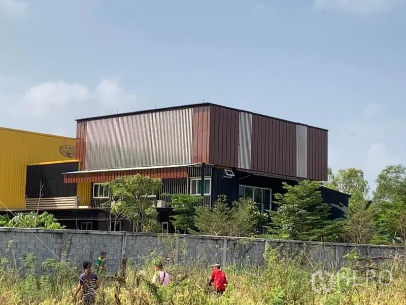 工厂 出售在Thanyaburi, Pathum Thani - 主厂房旁的两层金属覆面办公楼，周围绿化与围墙。