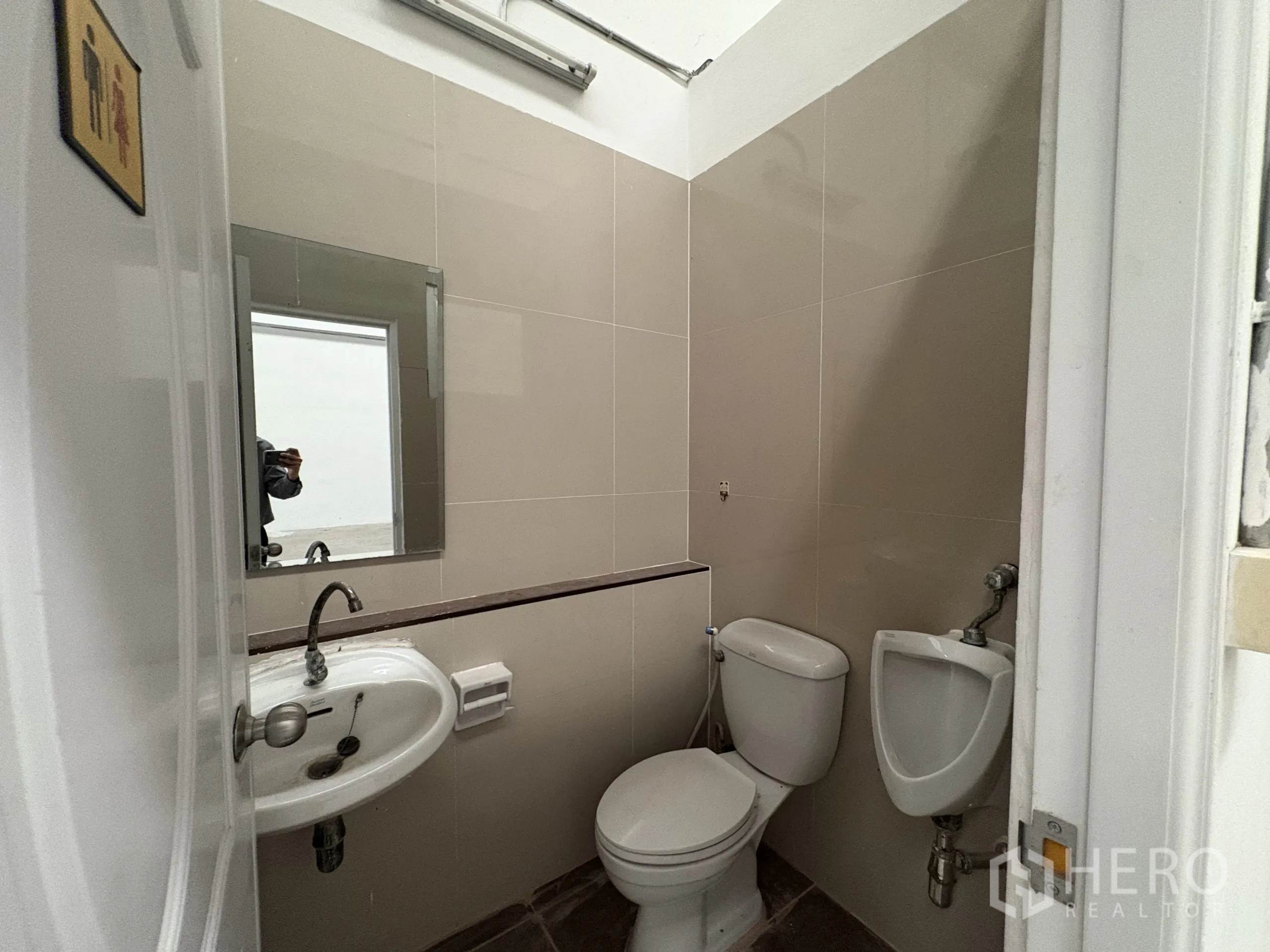 Factory for rent in Phra Samut Chedi, Samut Prakan - Tiled restroom with toilet, urinal, sink and mirror inside the unit.